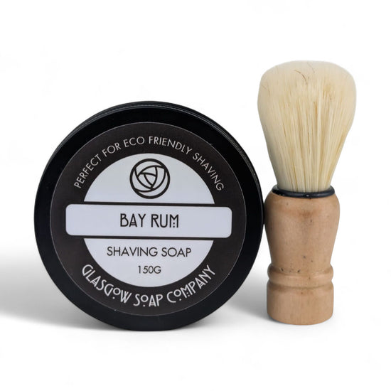 Shaving soap in a black container with a wooden brush on a white background