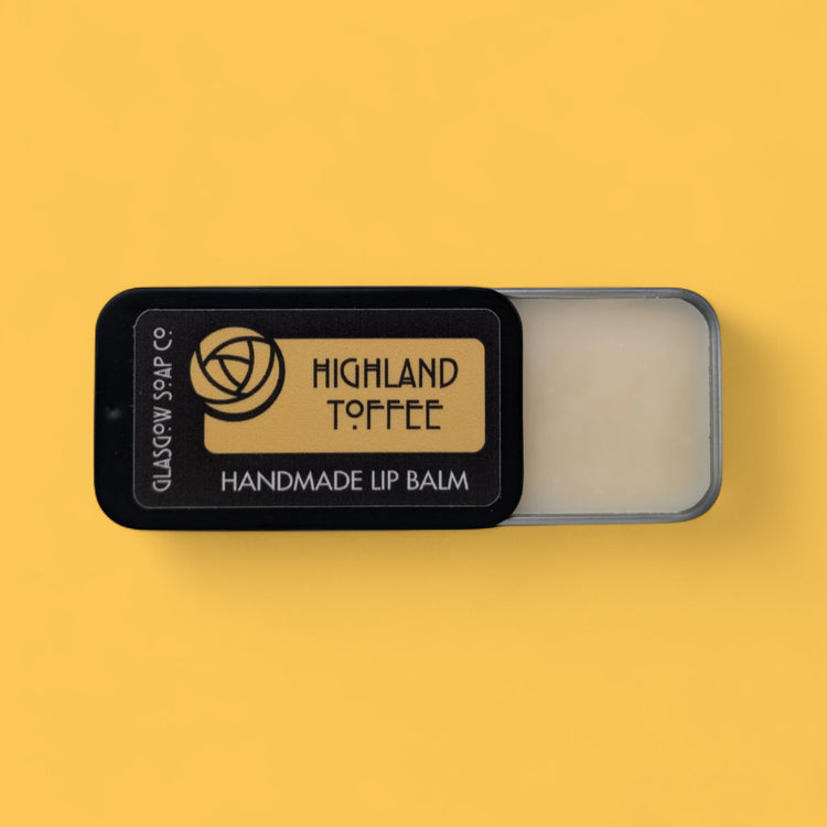Handmade lip balm in a black container with 'Highland Toffee' branding on a yellow background.