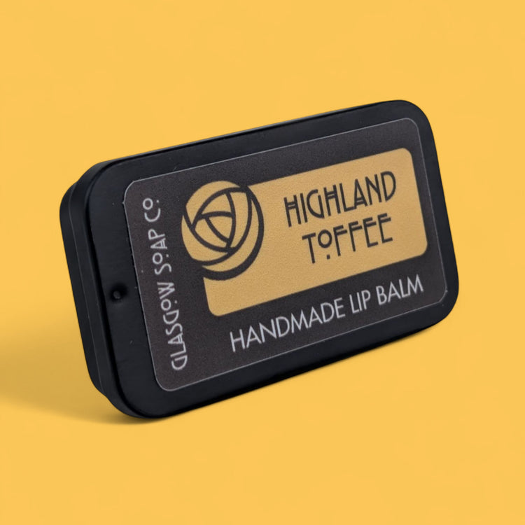 Handmade lip balm with 'Highland Toffee' flavor on a yellow background