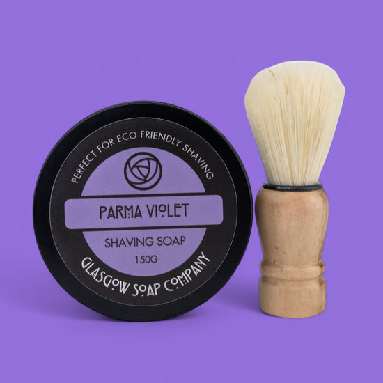 Shaving soap container and brush on a purple background