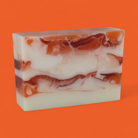 Marbled soap bar with brown and white swirls on an orange background