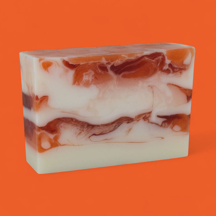 Marbled soap bar with brown and white swirls on an orange background