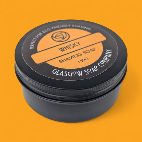 Shaving soap container with black lid and orange label on an orange background