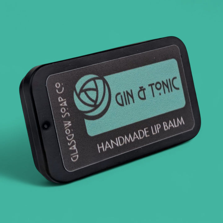 Handmade lip balm packaging with 'Gin & Tonic' branding on a teal background