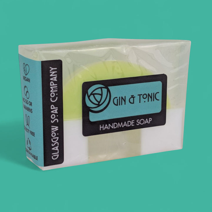 Handmade soap in clear packaging with 'Gin & Tonic' branding on a teal background