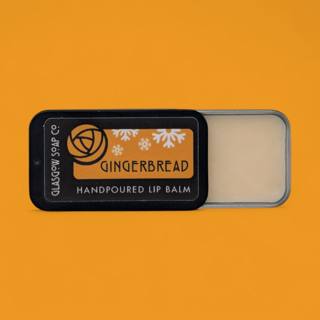 Gingerbread christmas lip balm tin with 'Glasgow Soap Co' branding on an orange background