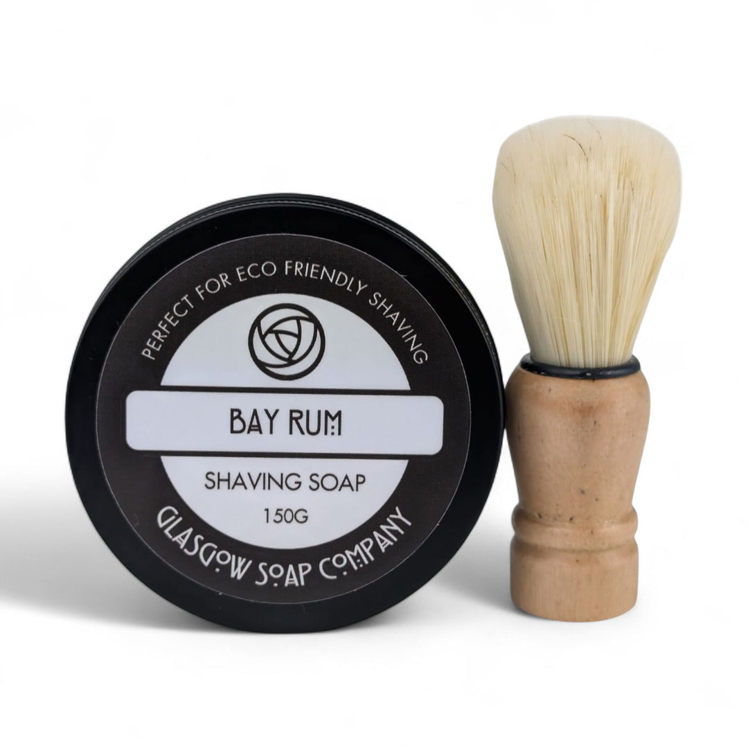 Shaving soap in a black container with a wooden brush on a white background