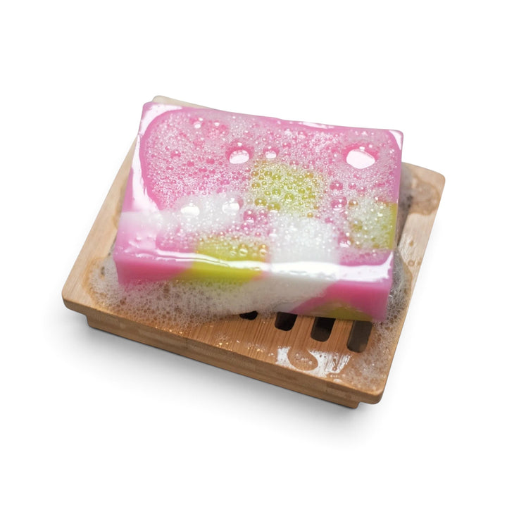 Glasgow Soap Company Ltd Scottish Rose soap bar with pink and green swirls in a lather on a wooden soap dish