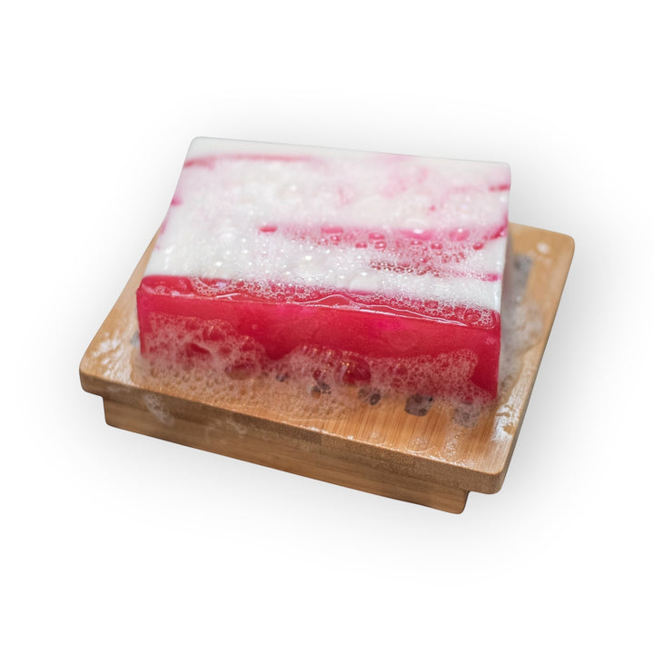 Glasgow Soap Company Ltd Raspberry Ripple soap bar with pink and white layers, on a wooden soap dish with lather.