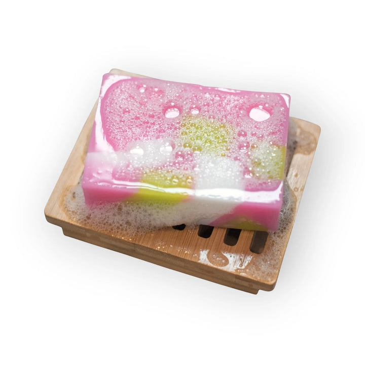 Glasgow Soap Company Ltd Scottish Rose soap bar with pink, white, and green swirls, on a bamboo soap dish with lather.