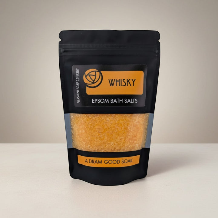 Glasgow Soap Company Ltd Whisky Epsom Bath Salts in a black pouch with a clear window showing orange salts. Relaxing bath soak.