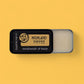 Handmade lip balm in a black container with 'Highland Toffee' branding on a yellow background.