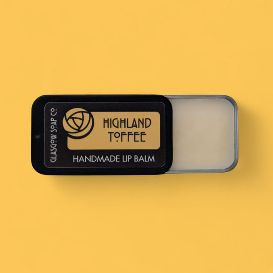 Handmade lip balm in a black container with 'Highland Toffee' branding on a yellow background.