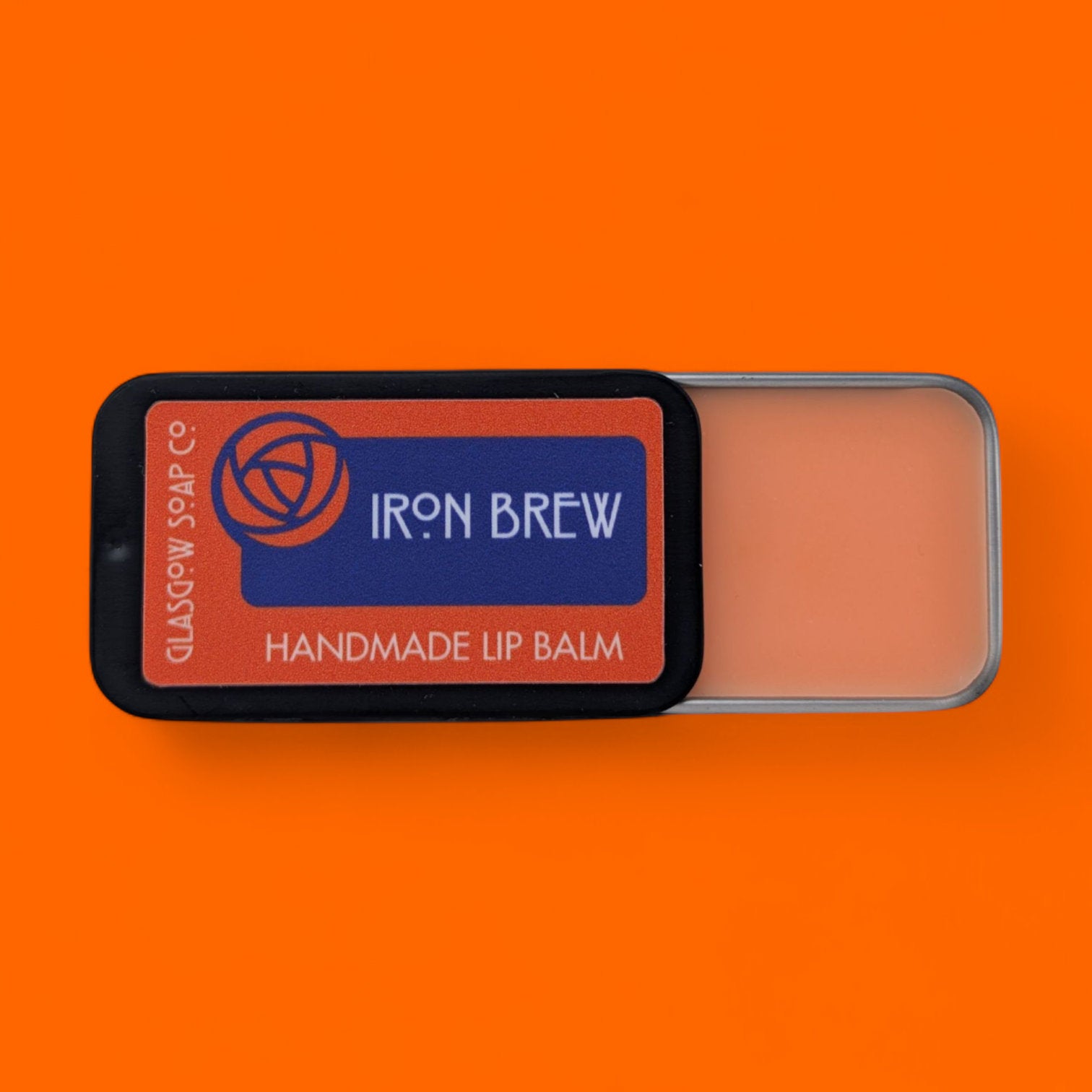 Handmade lip balm with 'Iron Brew' label on an orange background