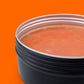 Black container with a silver lid on an orange background