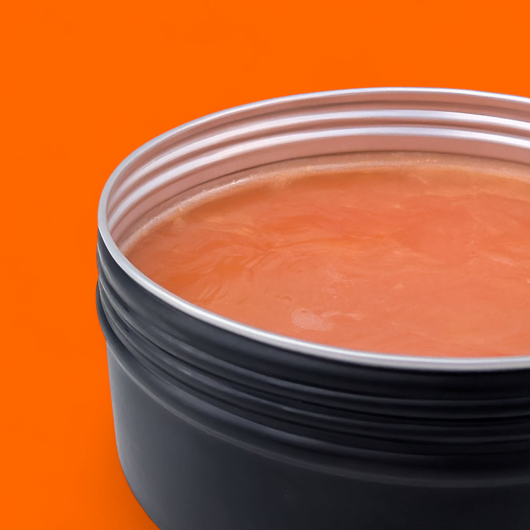 Black container with a silver lid on an orange background