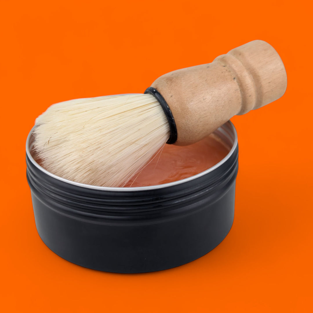 Shaving brush and black container on an orange background