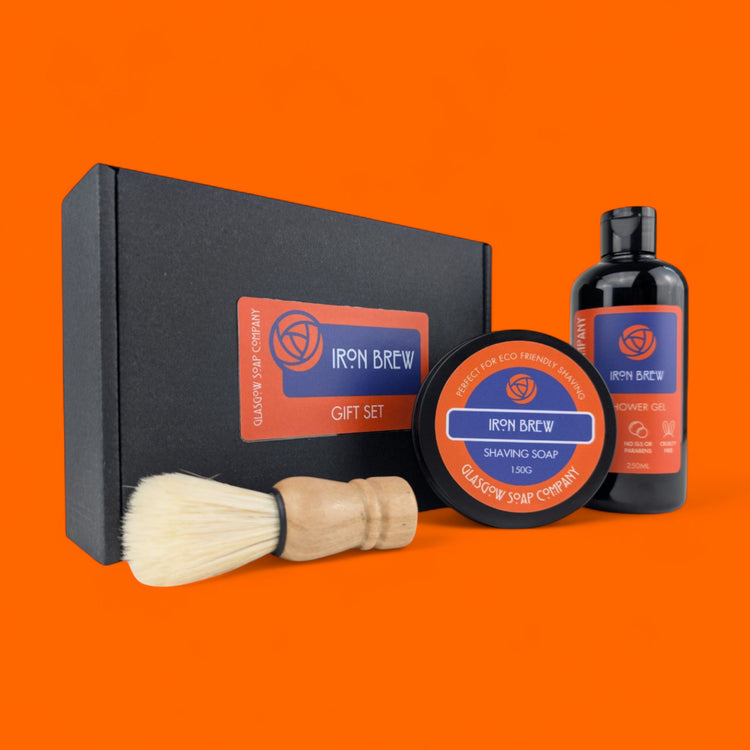 Iron Brew irn bru unisex shaving grooming gift set with a vegan brush, shaving soap, and shower gel on an orange backgrounding 