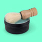 Shaving brush and black container on a green background