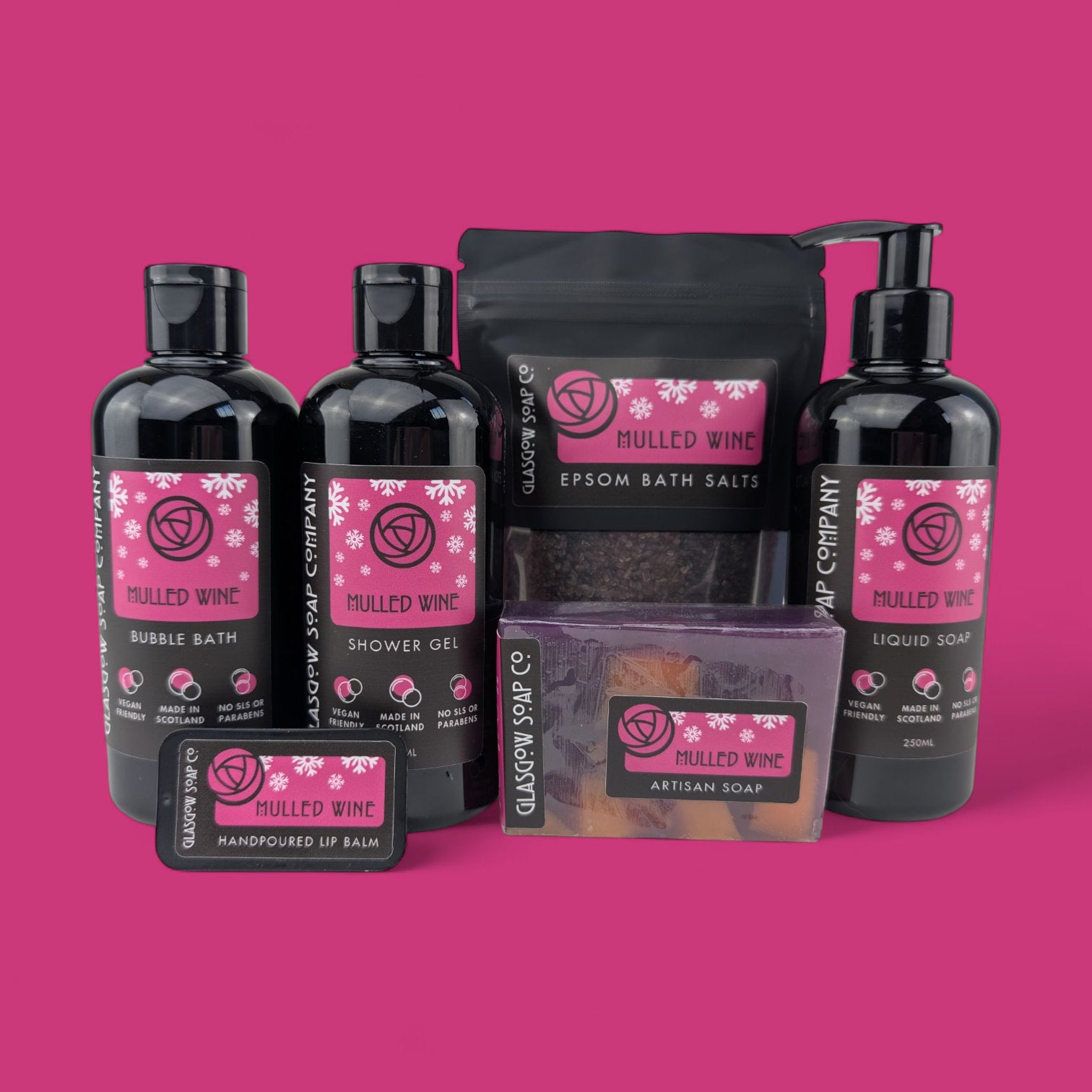Collection of mulled wine-themed christmas bath and body products from glasgow soap company on a pink background