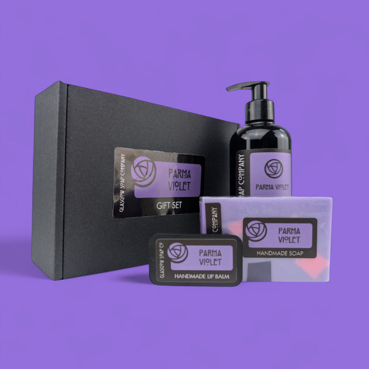 Parma Violet gift set with black box, soap, lotion, and balm on a purple background