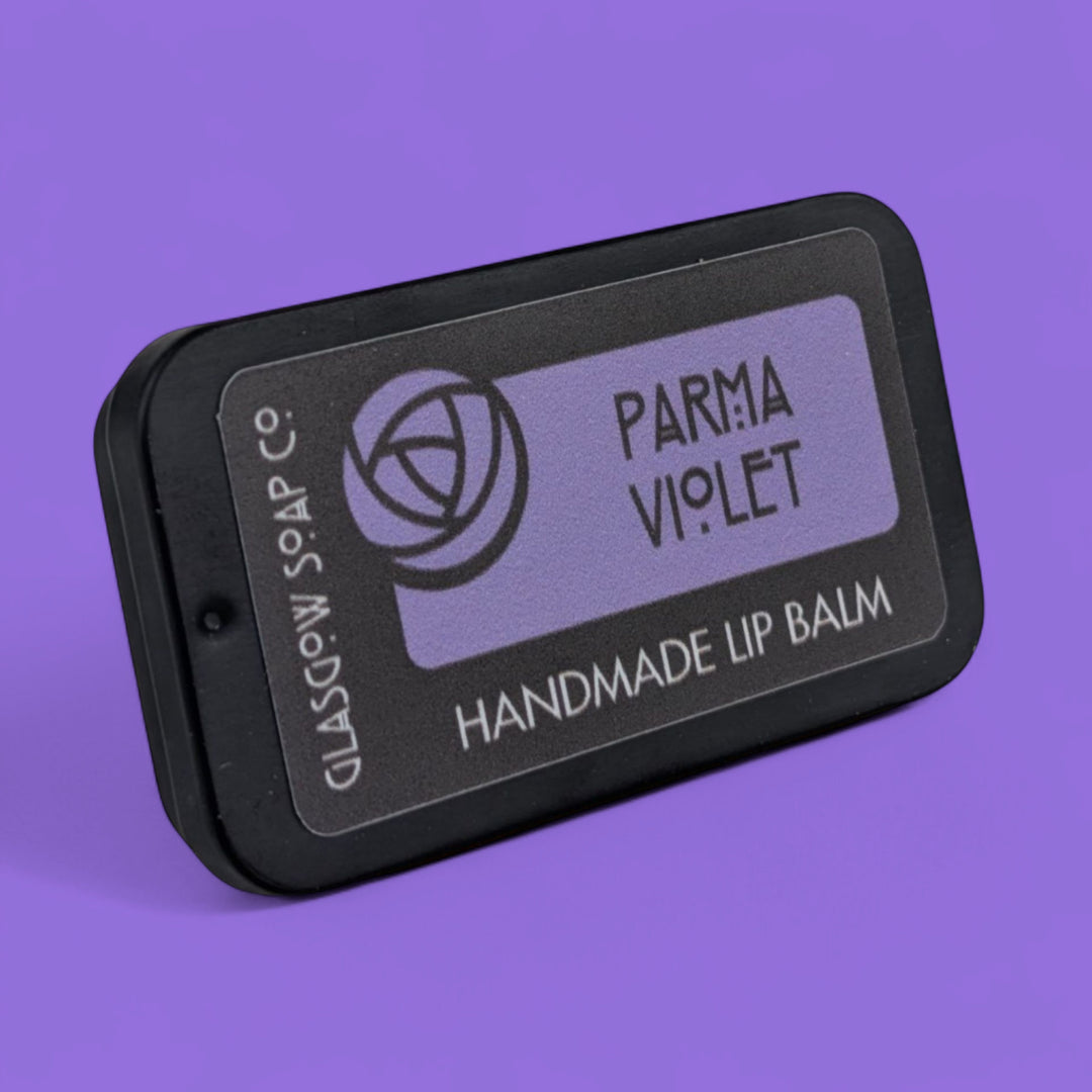 Handmade lip balm packaging with 'Parma Violet' on a purple background