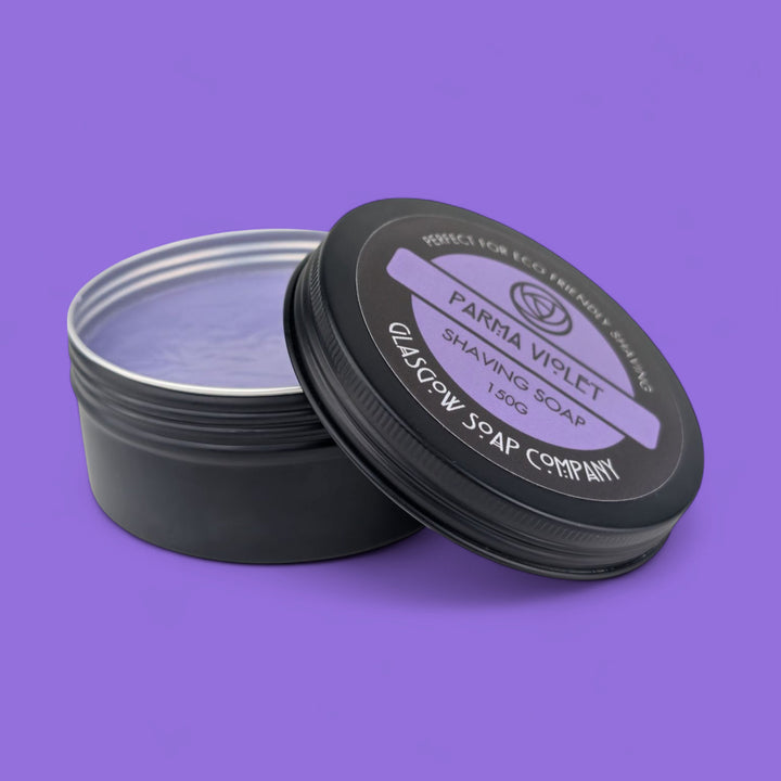 Shaving soap in a black container with 'Parma Violet' label on a purple background
