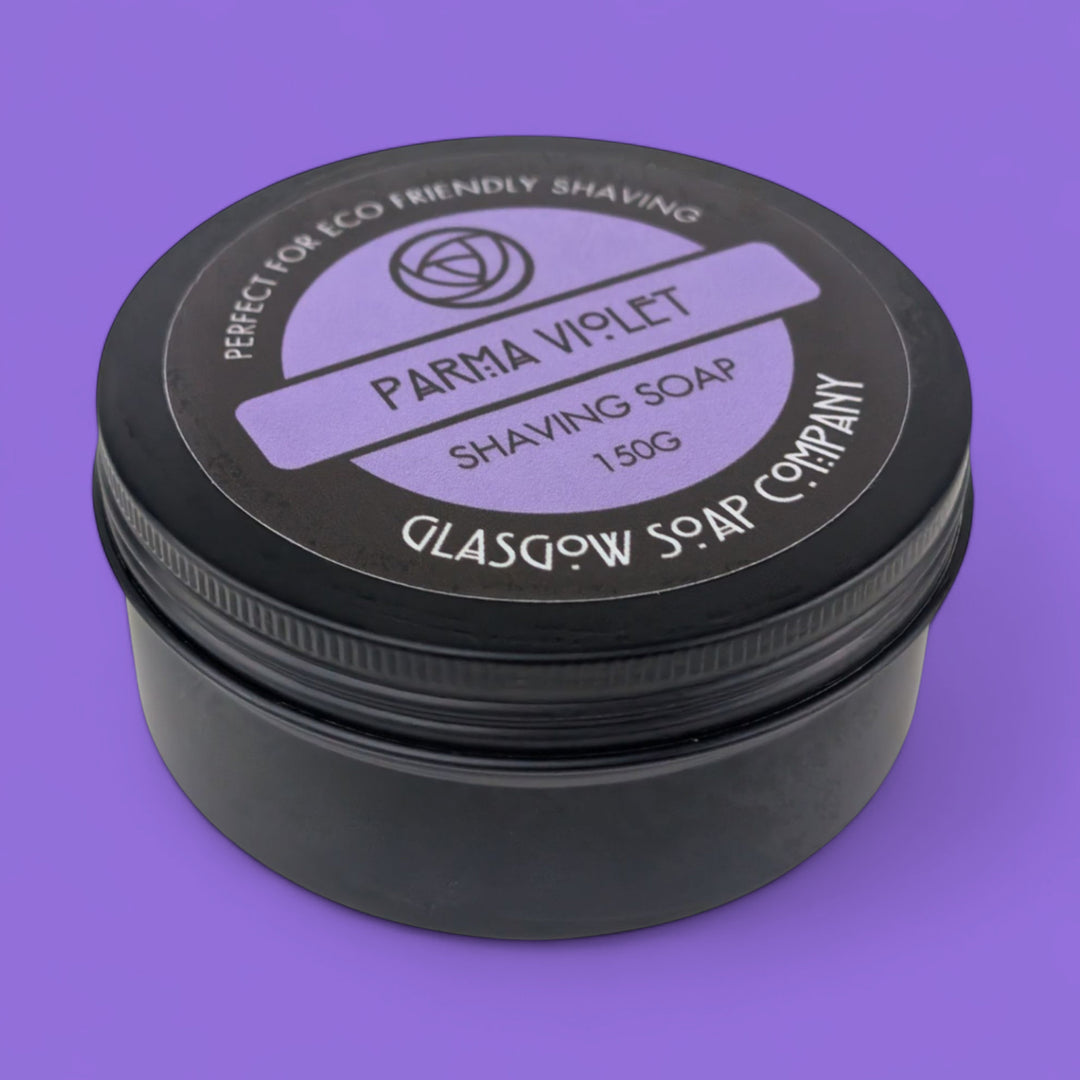 Black container of Parma Violet shaving soap with a purple background