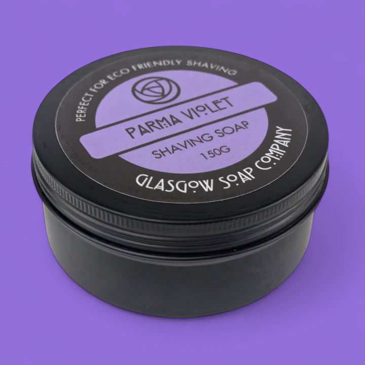 Black container of Parma Violet shaving soap with a purple background
