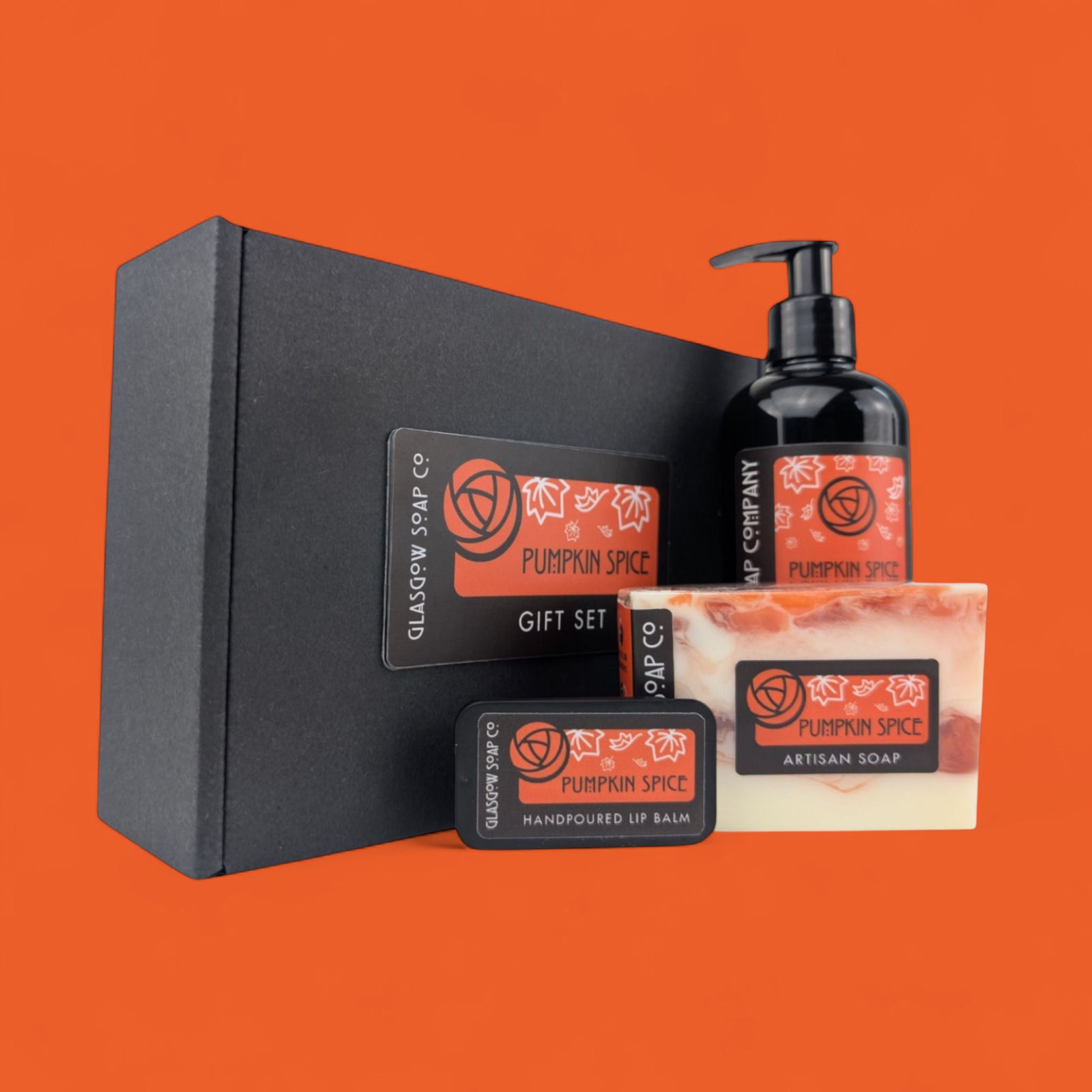 Pumpkin Spice gift set with soap, liquid soap, and lip balm on an orange background