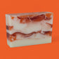 Marbled soap bar with brown and white swirls on an orange background