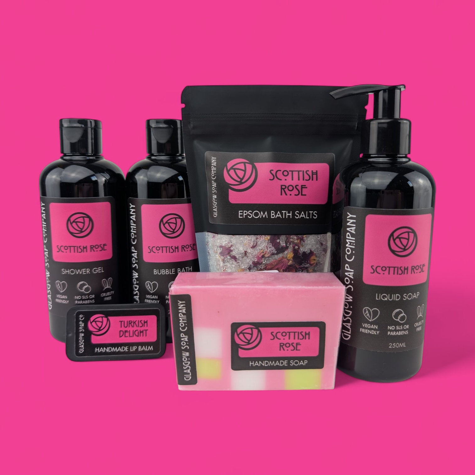 Collection of Scottish Rose bath and body products on a pink background