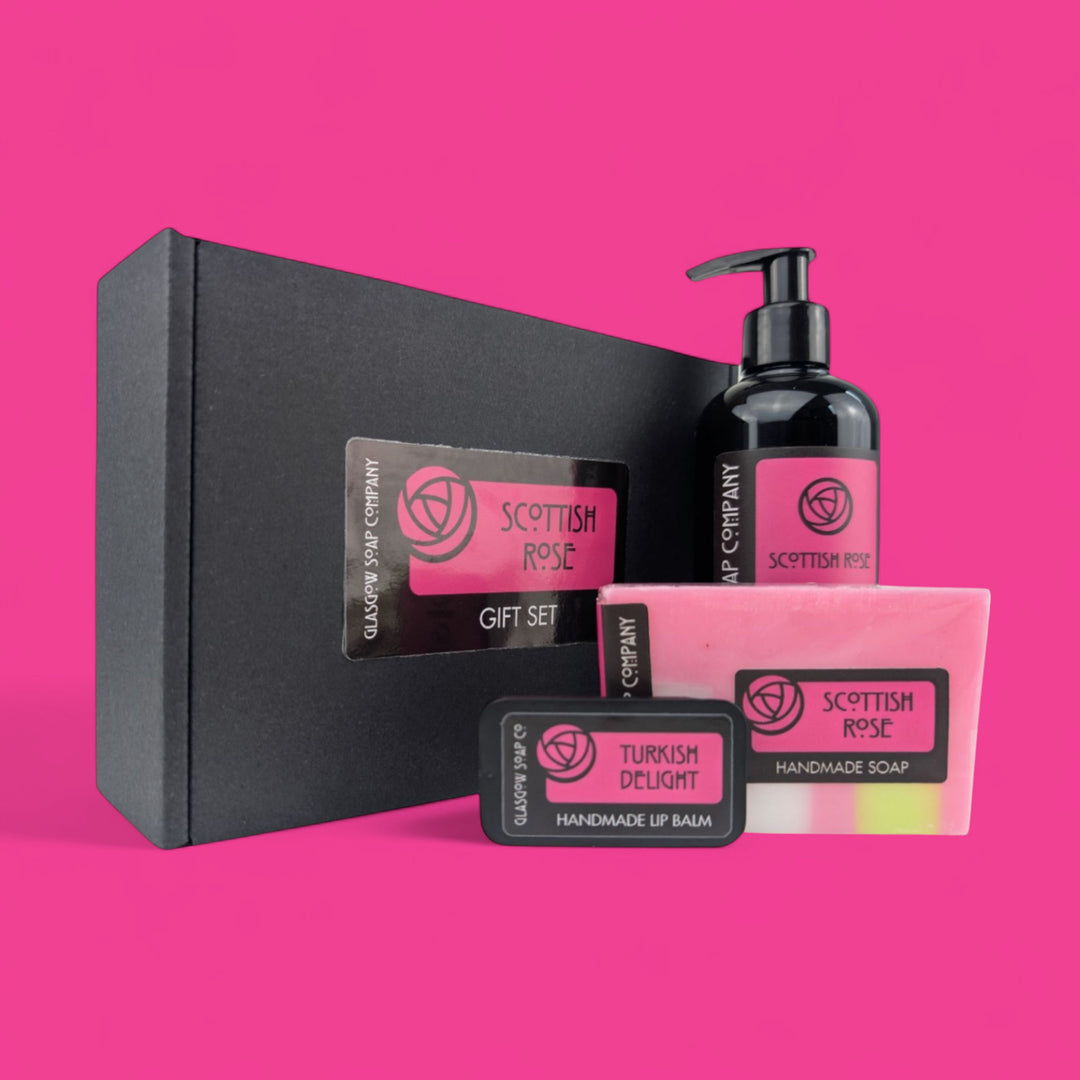 Scottish Rose gift set with black box, soap, liquid soap, and lip balm on a pink background