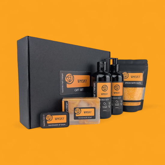 Whisky-themed gift set with bottles, boxes, and packaging on an orange background
