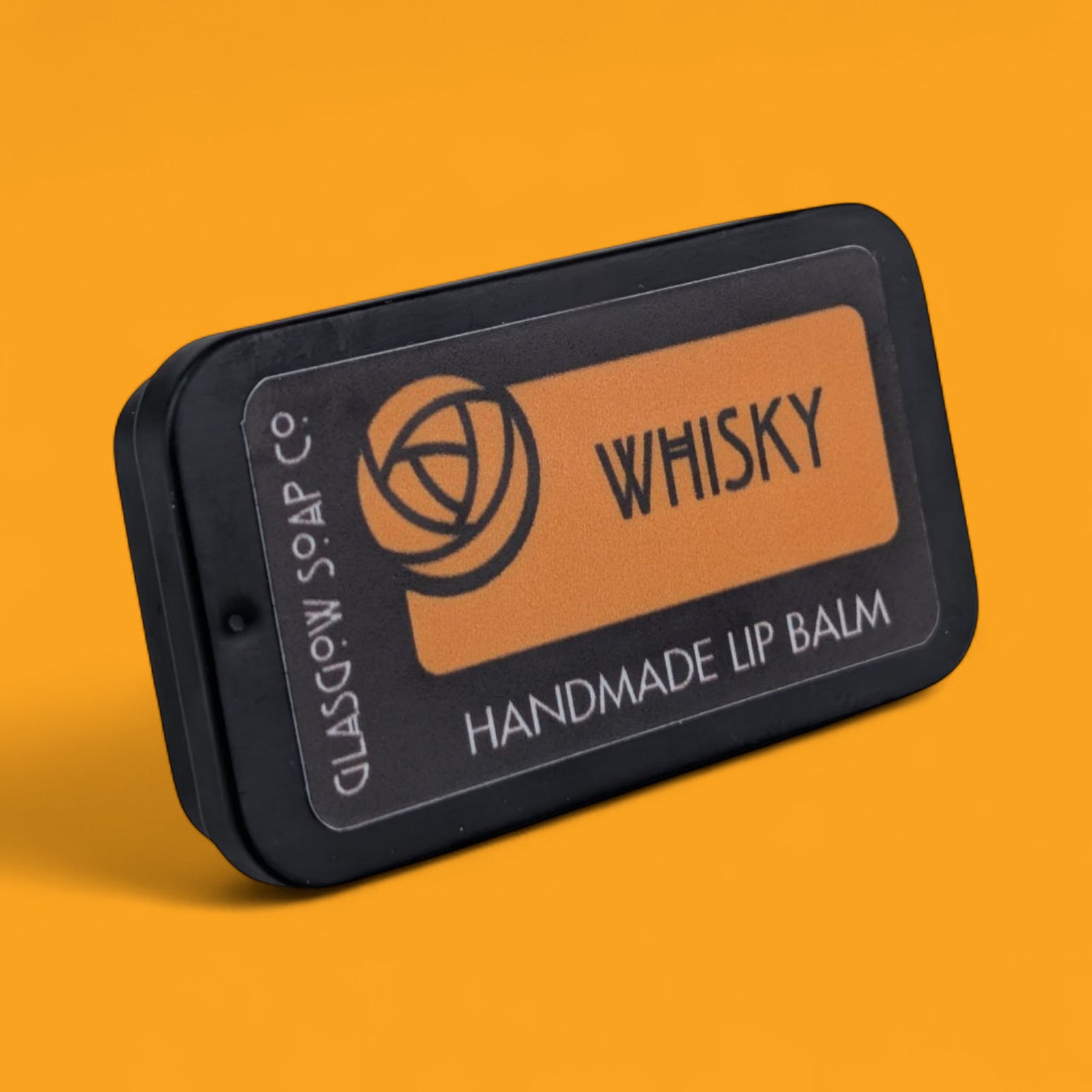 Handmade lip balm packaging with 'Whisky' branding on an orange background