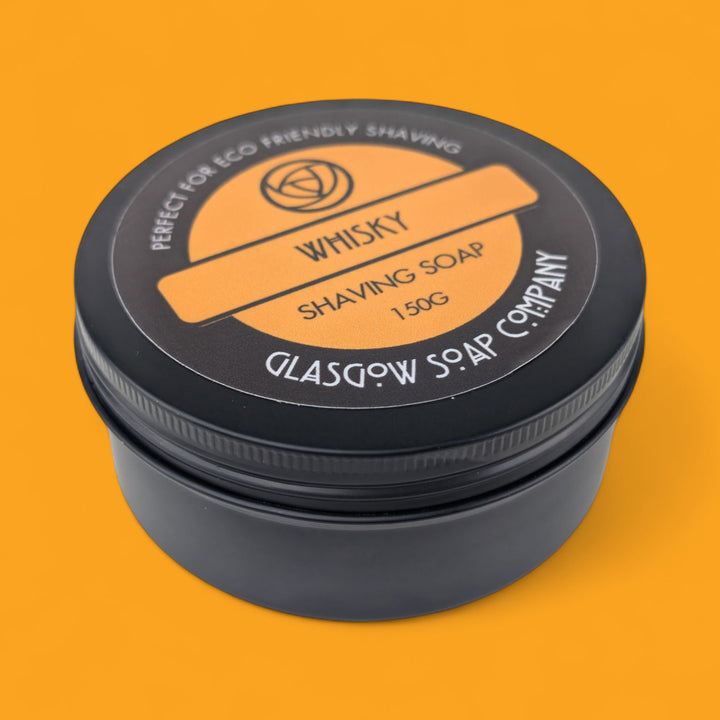 Shaving soap container with black lid and orange label on an orange background