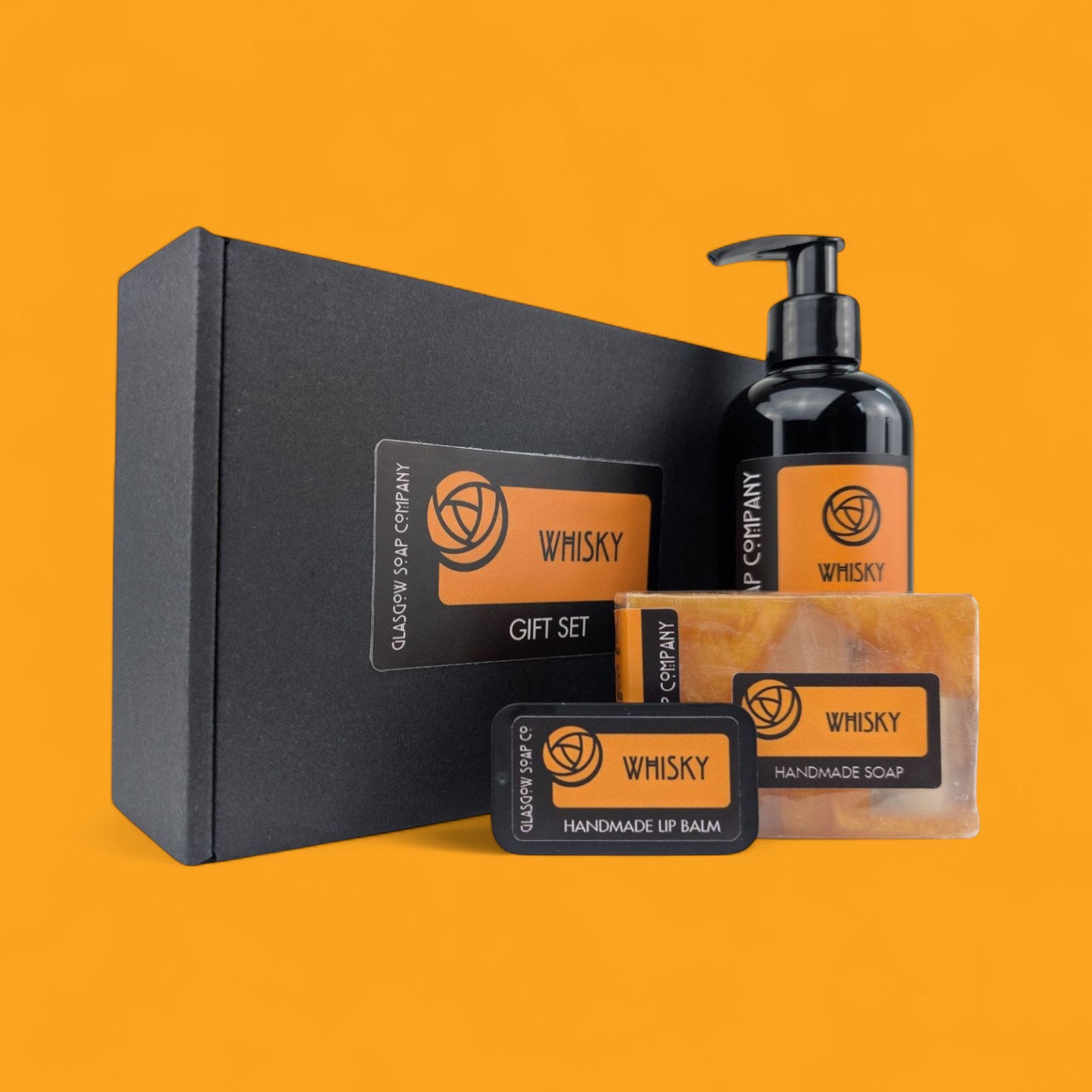 Whisky Gift Set with black box, soap, lip balm, and liquid soap bottle on a gold background
