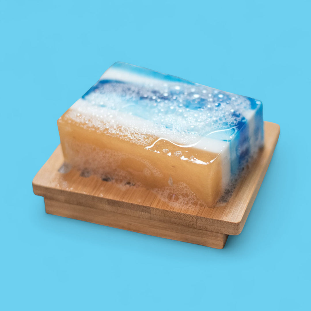 Bar of soap with a wooden soap dish on a blue background