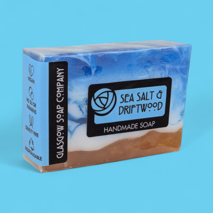 Handmade soap bar with 'Sea Salt & Driftwood' label on a blue background
