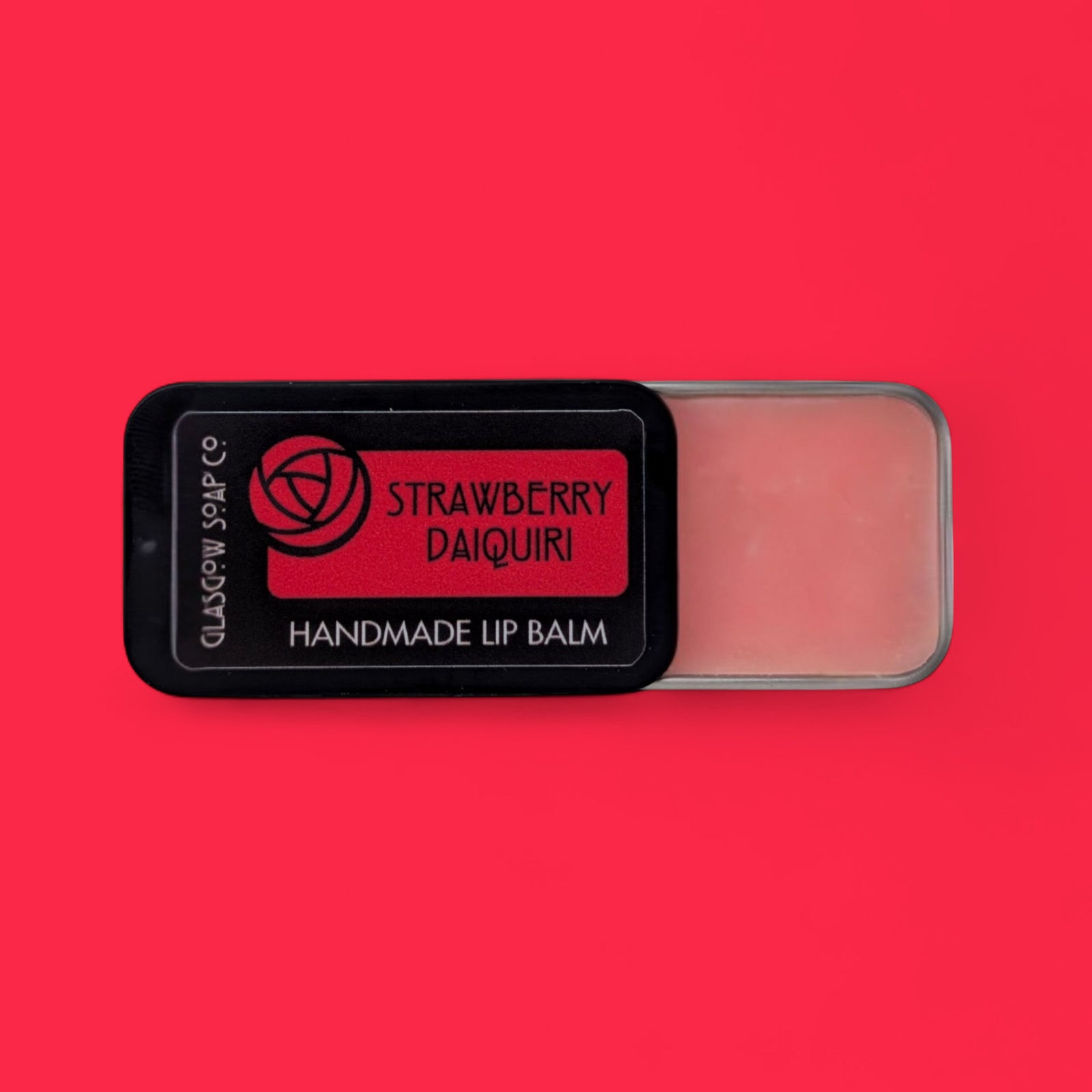 Handmade lip balm labeled 'Strawberry Daiquiri' on a red background