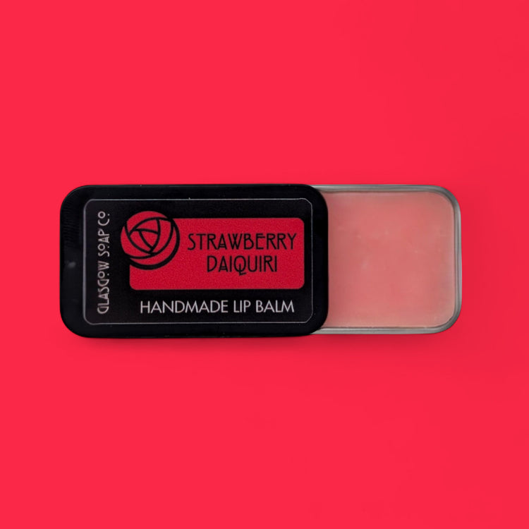 Handmade lip balm labeled 'Strawberry Daiquiri' on a red background