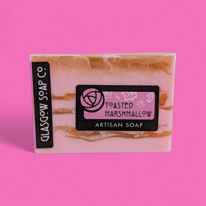 Artisan soap bar with 'Toasted Marshmallow' flavor on a pink background
